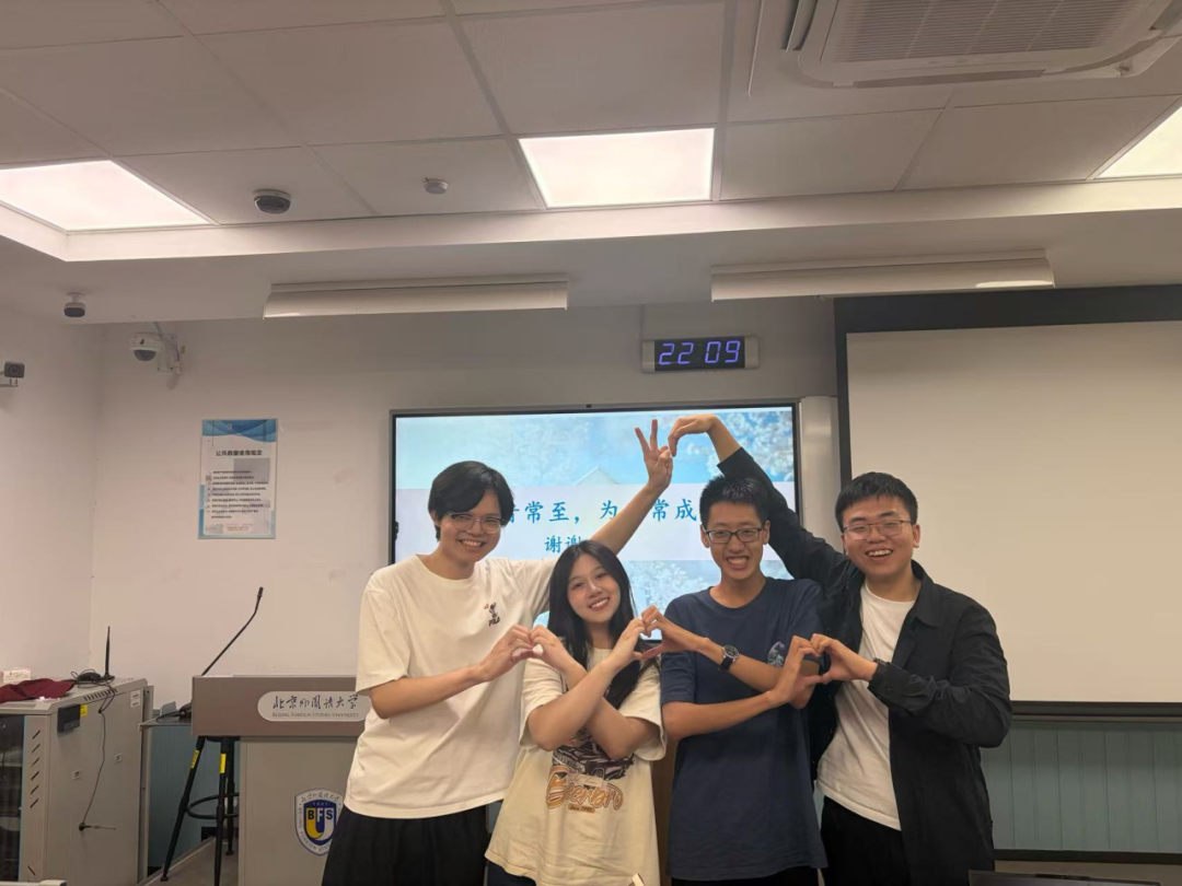 四名助理部成员在教室里用手势组成爱心合影